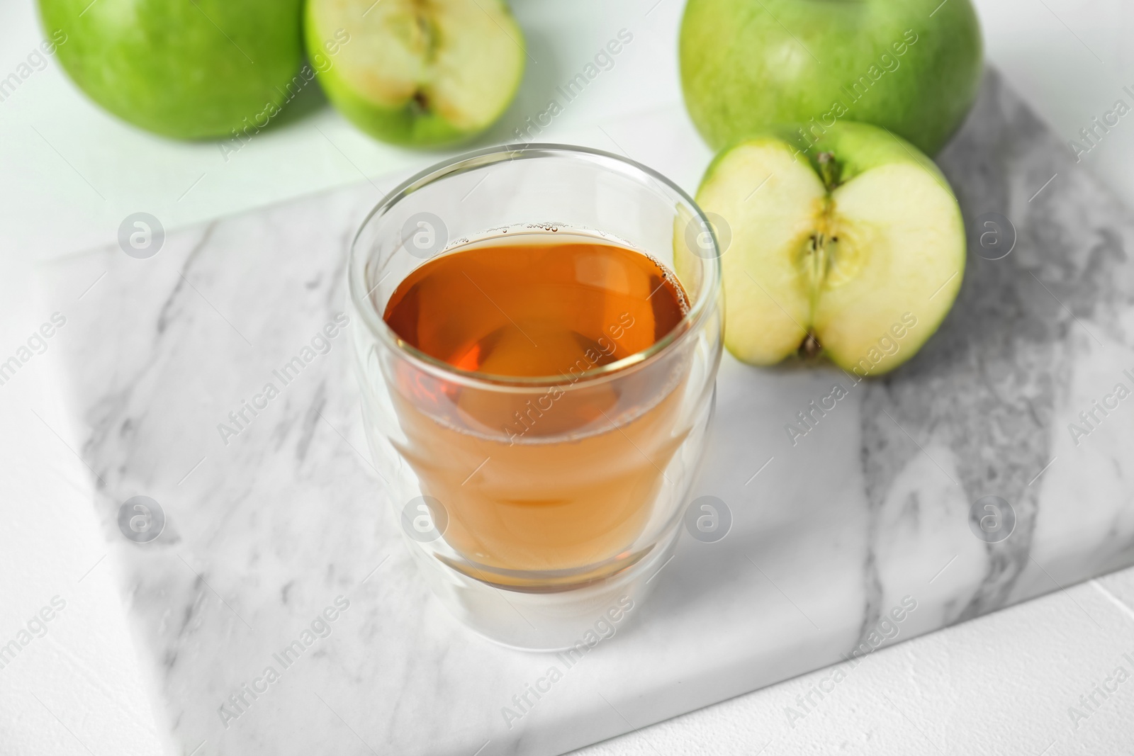 Photo of Glass of apple juice on marble board