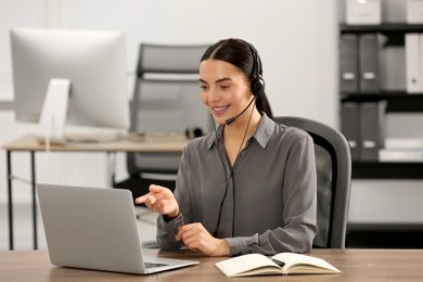 Hotline operator with headset working on laptop in office