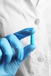 Photo of Doctor in medical glove holding pill, closeup view