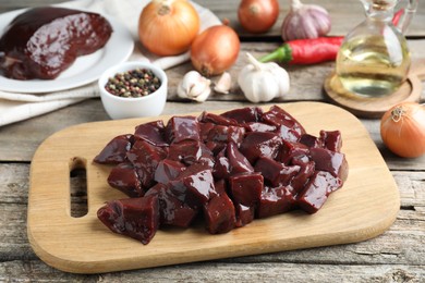 Photo of Cut raw beef liver and products on wooden table, closeup
