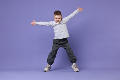 Happy little boy dancing on violet background