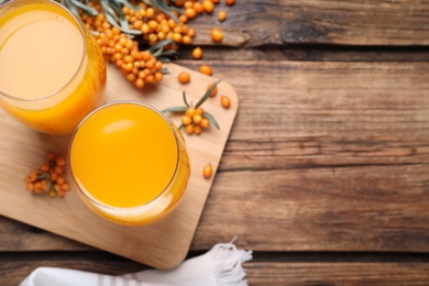 Photo of Sea buckthorn juice on wooden table, top view. Space for text