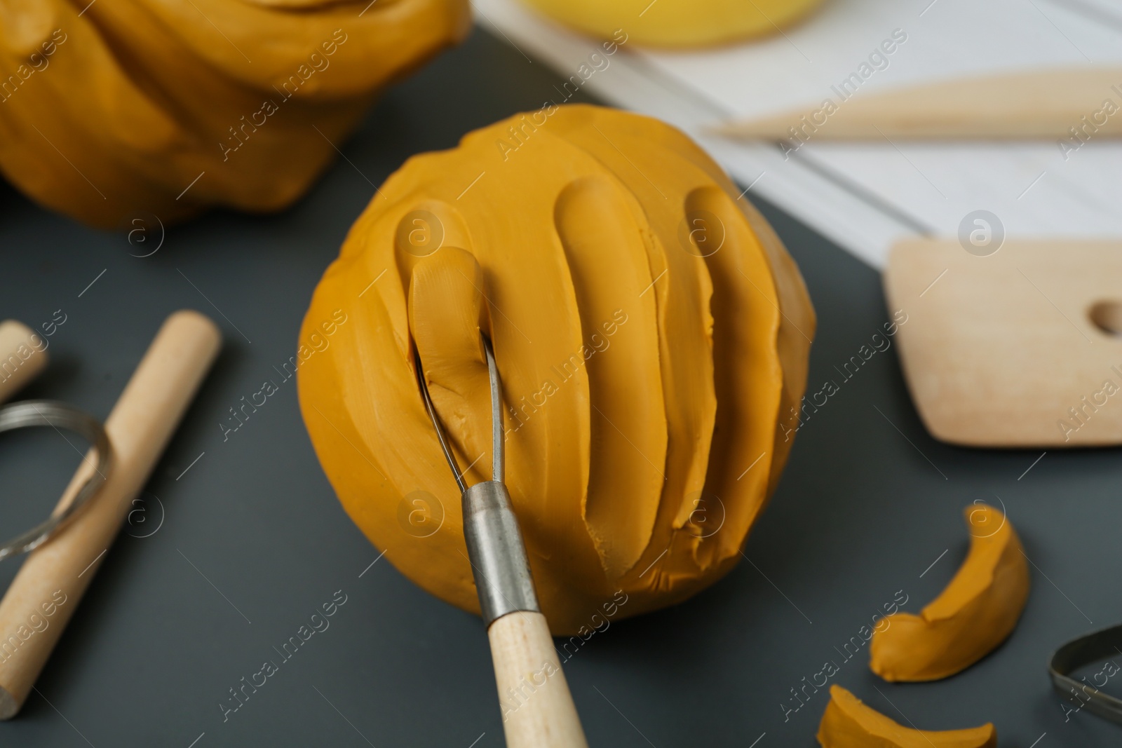 Photo of Clay and set of modeling tools on table, closeup