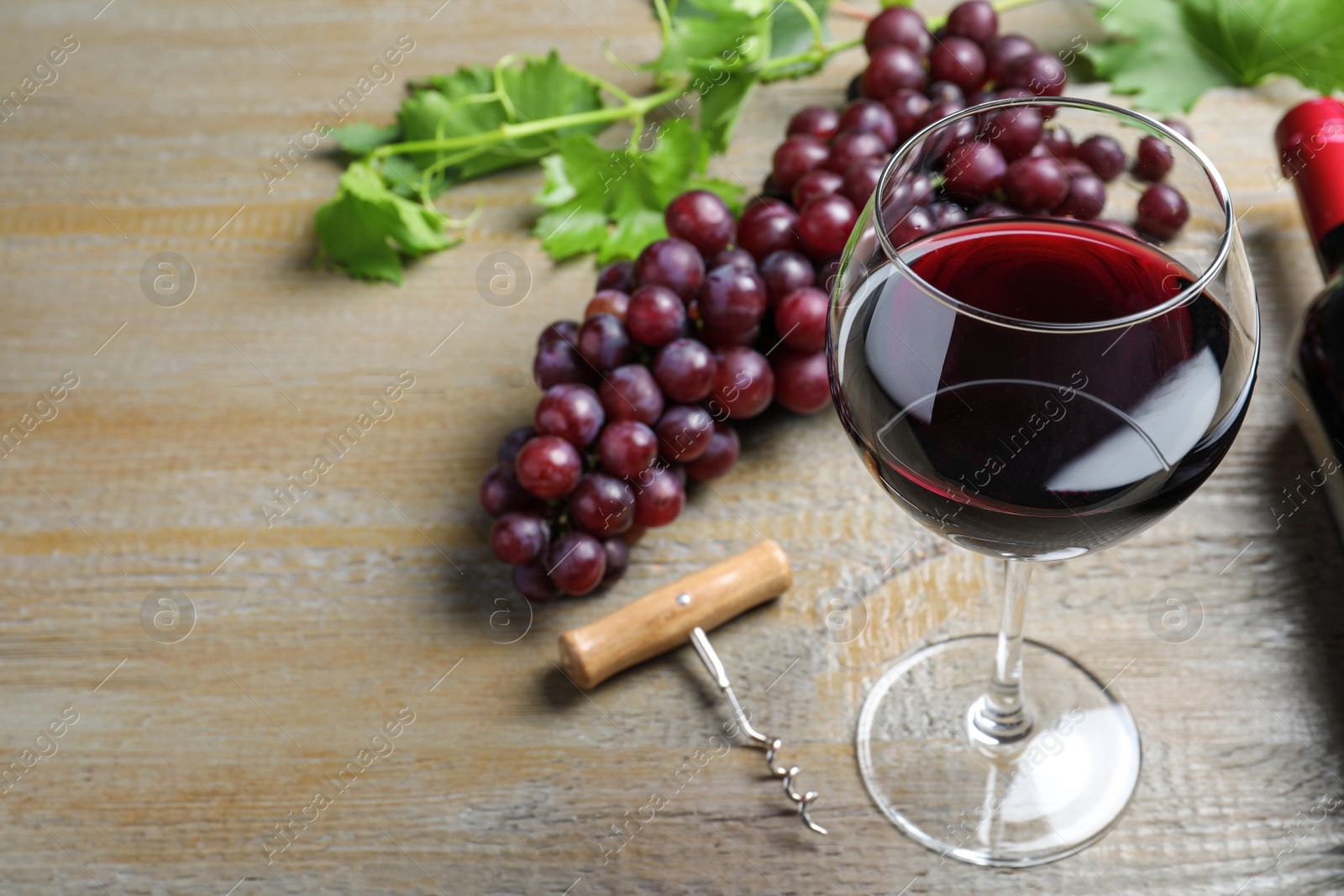 Photo of Fresh ripe juicy grapes and glass of wine on wooden table