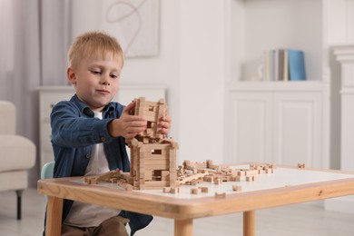 Cute little boy playing with wooden blocks at table indoors. Child's toy