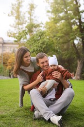 Happy parents with their adorable baby on green grass in park