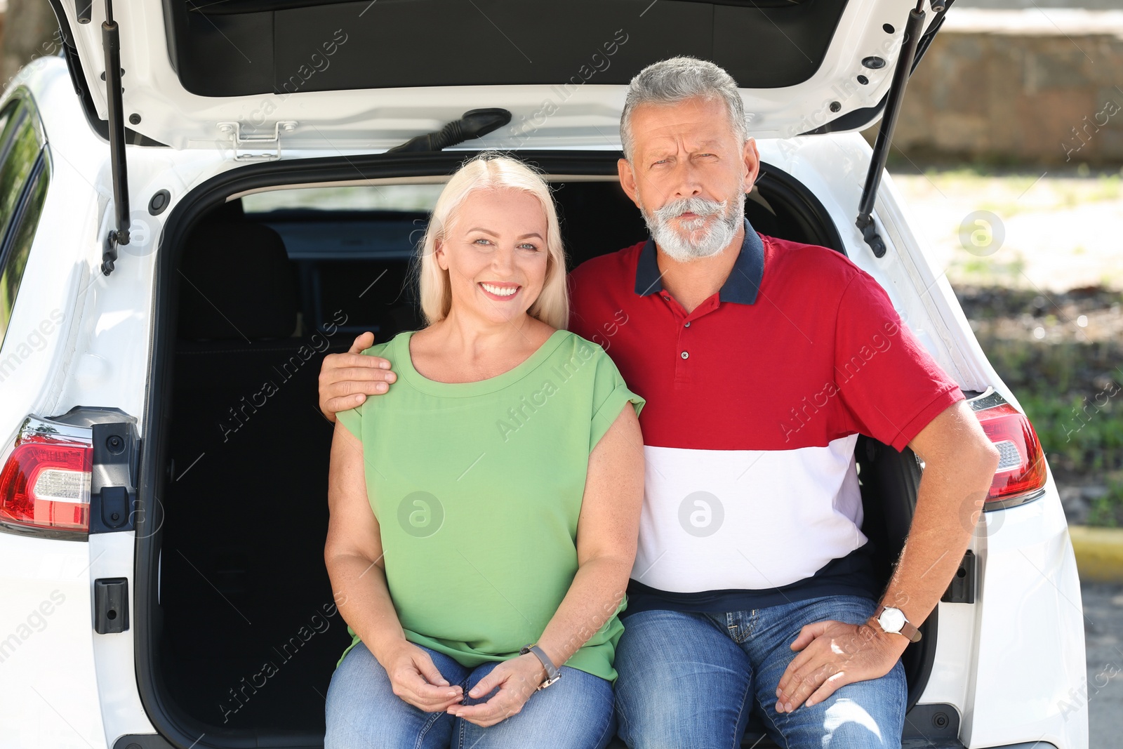 Photo of Happy senior couple sitting in their car trunk outdoors