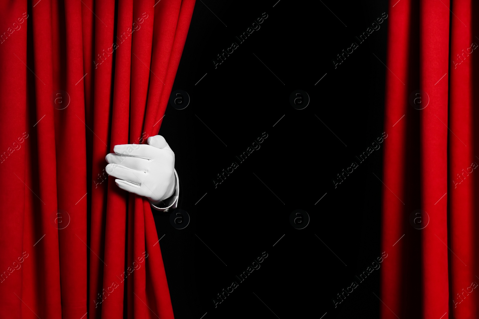 Photo of Person opening red front curtains on black background, closeup. Space for text