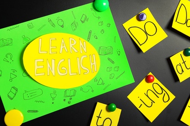 Photo of Sheet of paper with phrase Learn English on blackboard, closeup