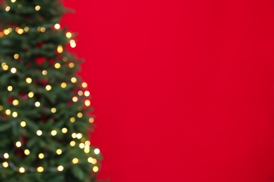 Photo of Blurred view of beautiful Christmas tree with fairy lights on red background