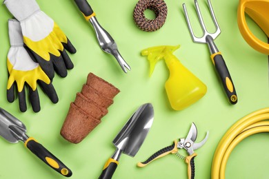 Photo of Flat lay composition with gardening tools on green background