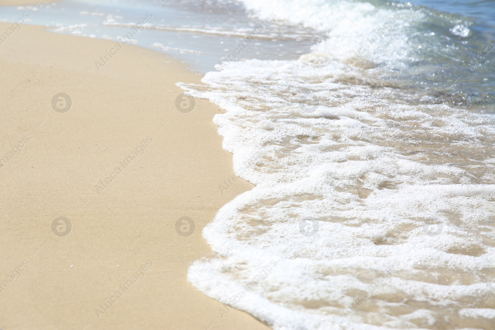 Photo of Beautiful sea waves on sandy beach, closeup