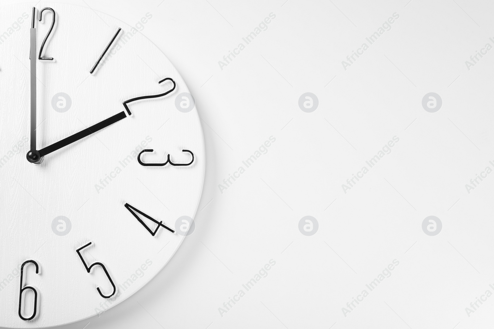 Photo of Stylish analog clock hanging on white wall, space for text