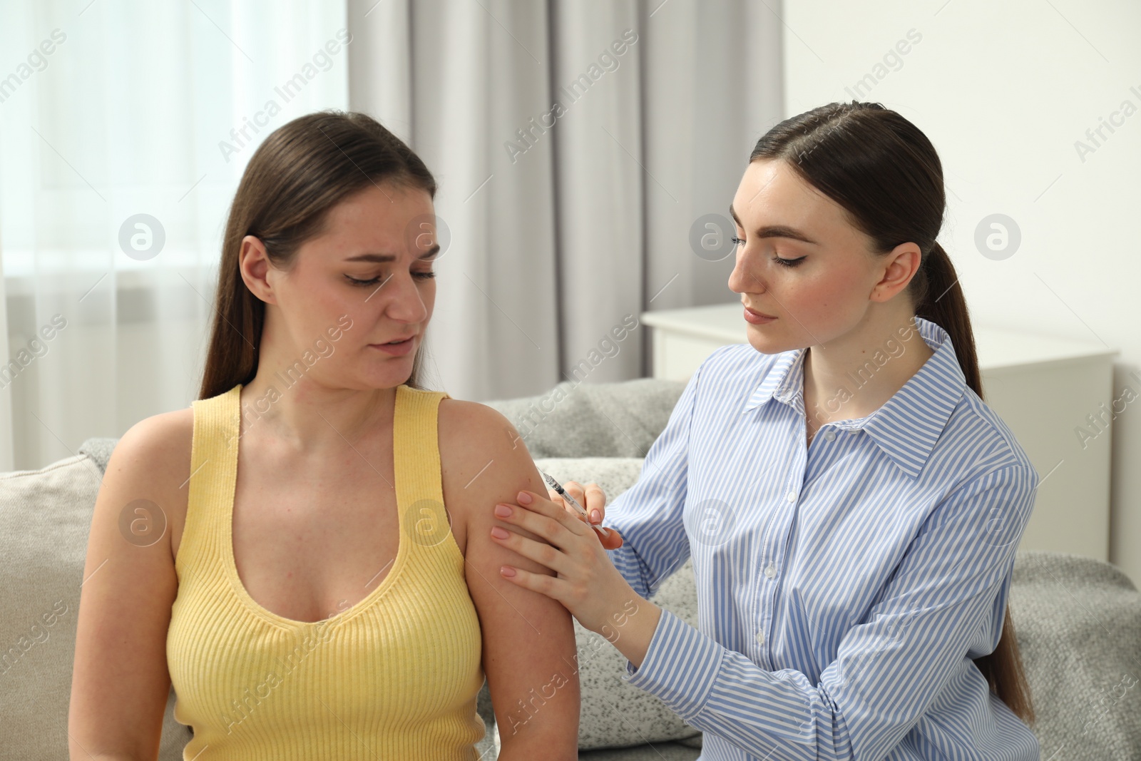 Photo of Woman giving insulin injection to her diabetic friend at home