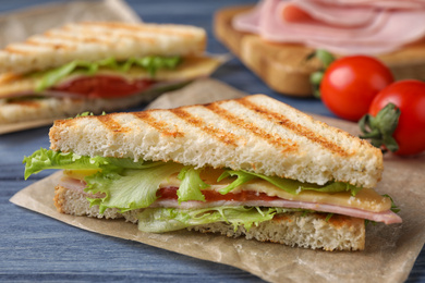 Photo of Tasty sandwich with ham on blue wooden table, closeup