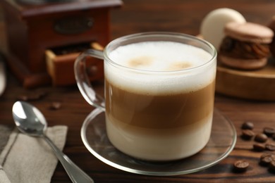 Aromatic coffee in cup, beans and spoon on wooden table, closeup