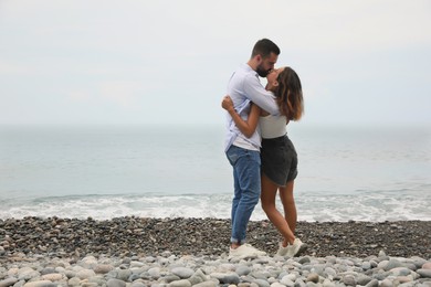 Photo of Young couple kissing on beach near sea. Space for text
