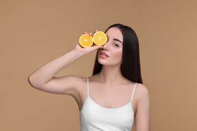 Photo of Beautiful young woman with pieces of orange on beige background