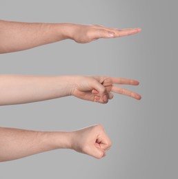 People playing rock, paper and scissors on grey background, closeup