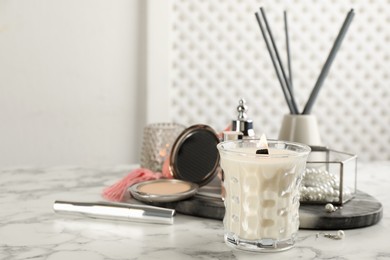 Composition with burning soy candle on white marble table, space for text