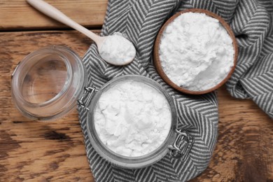 Photo of Bowl, spoon and glass jar of natural starch on wooden table, flat lay