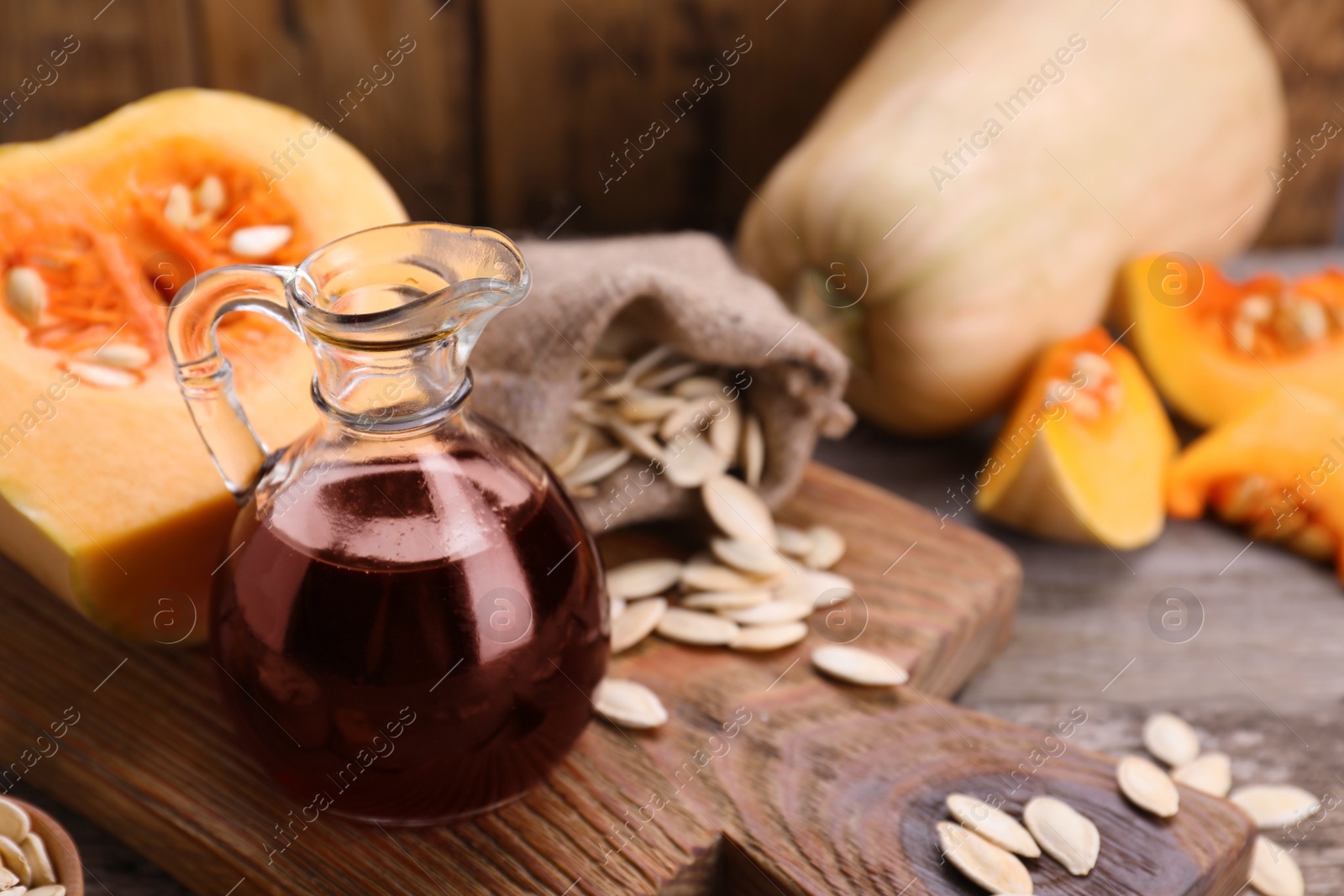 Photo of Fresh pumpkin seed oil in glass jug on wooden table