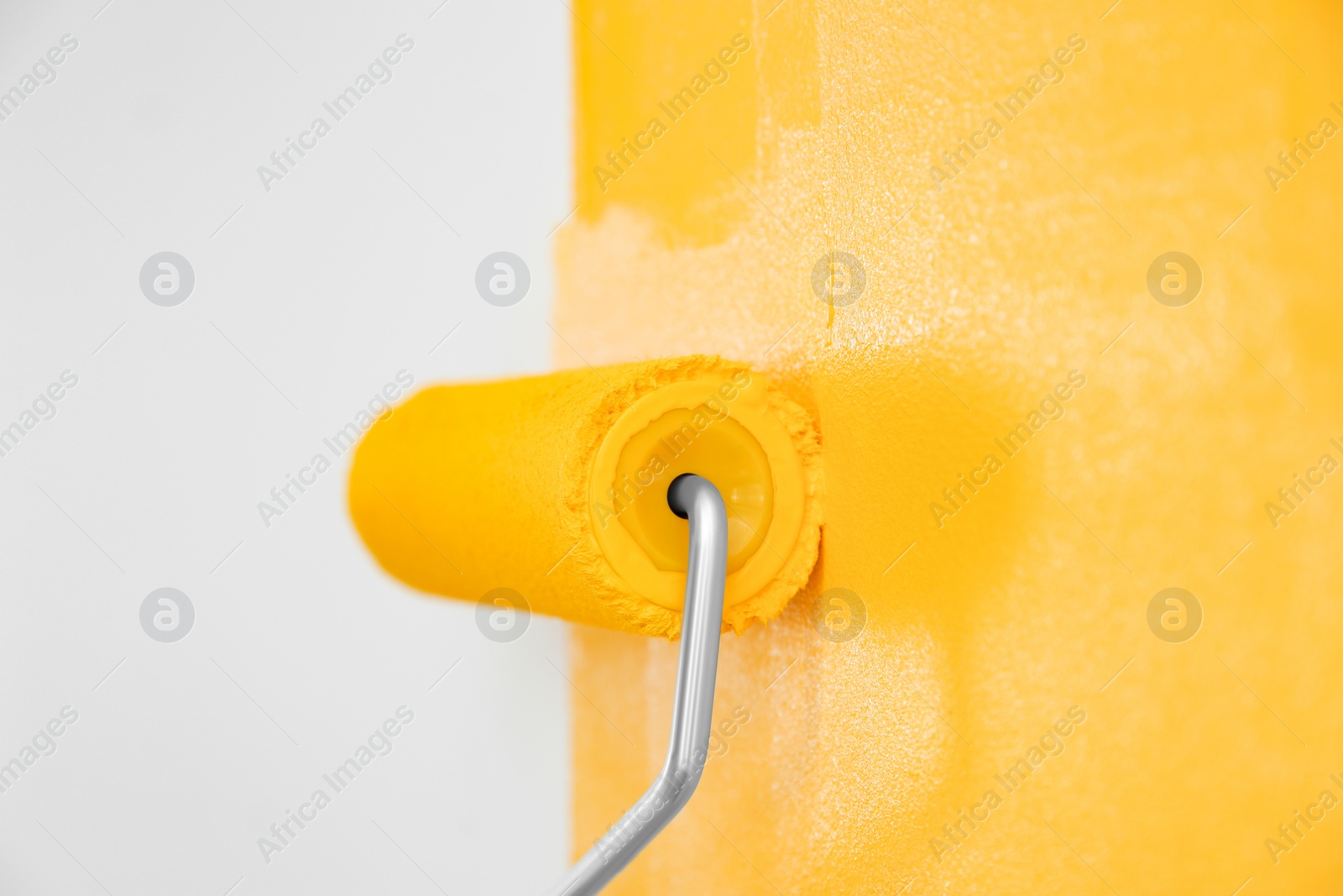 Photo of Painting white wall with yellow dye, closeup. Interior renovation