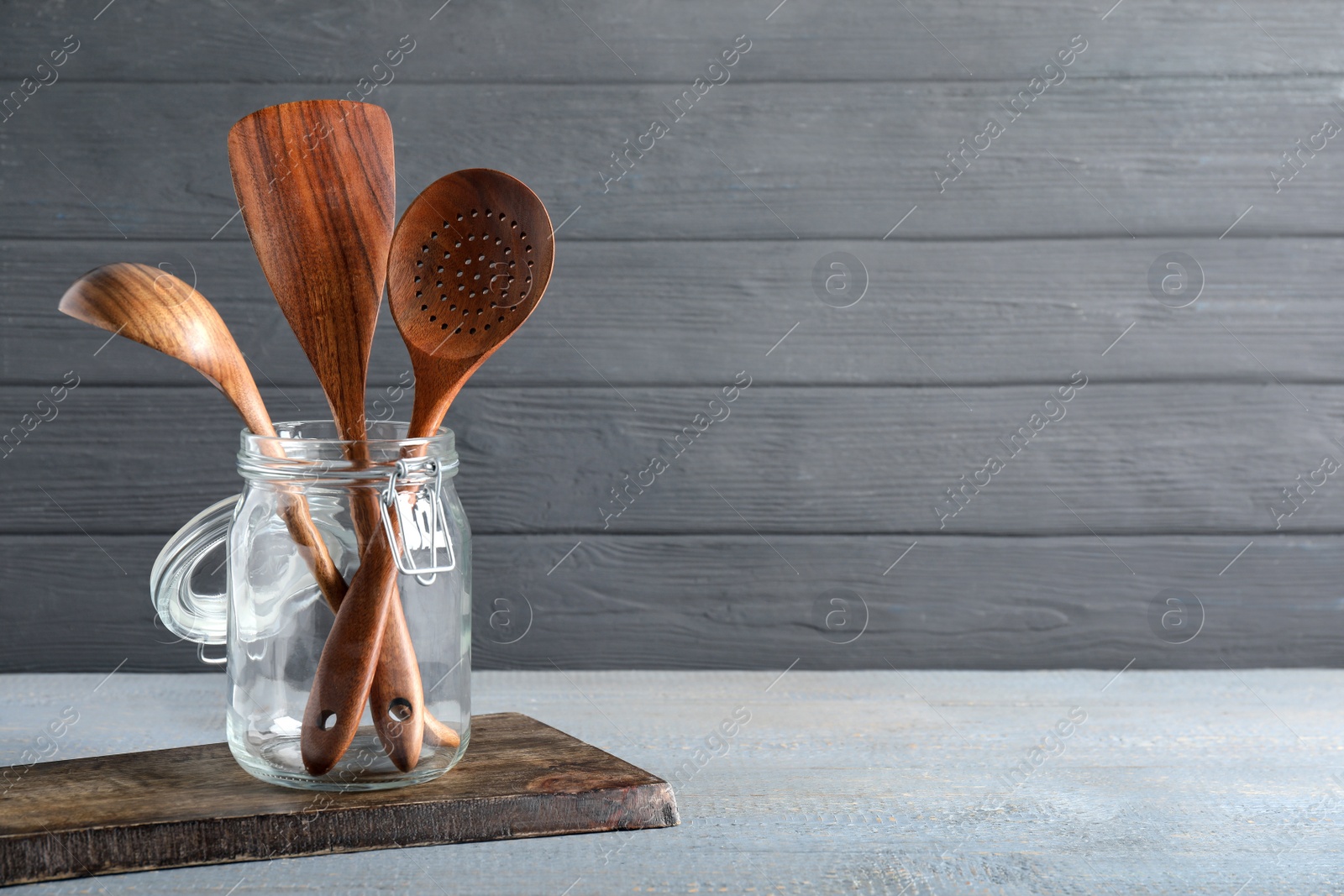 Photo of Set of kitchen utensils in holder on grey wooden table, space for text
