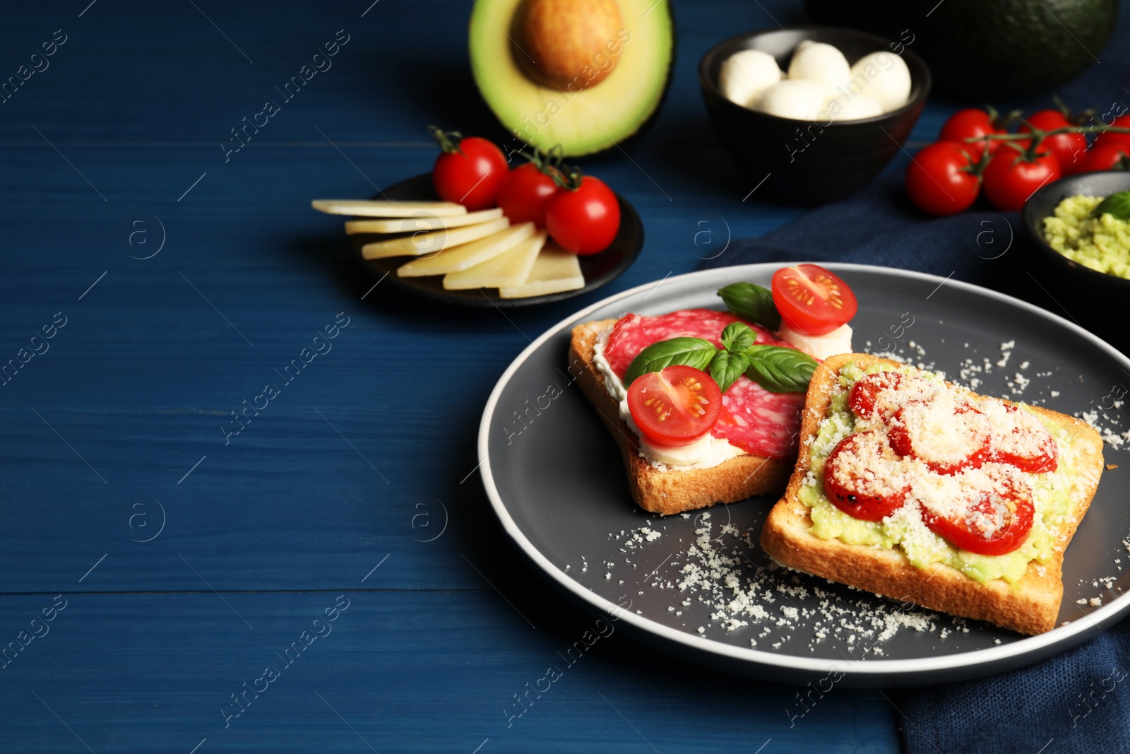 Photo of Tasty toasts with different toppings served on blue wooden table. Space for text
