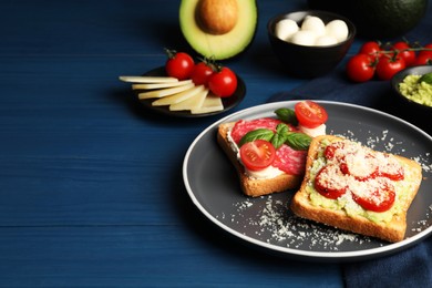 Tasty toasts with different toppings served on blue wooden table. Space for text