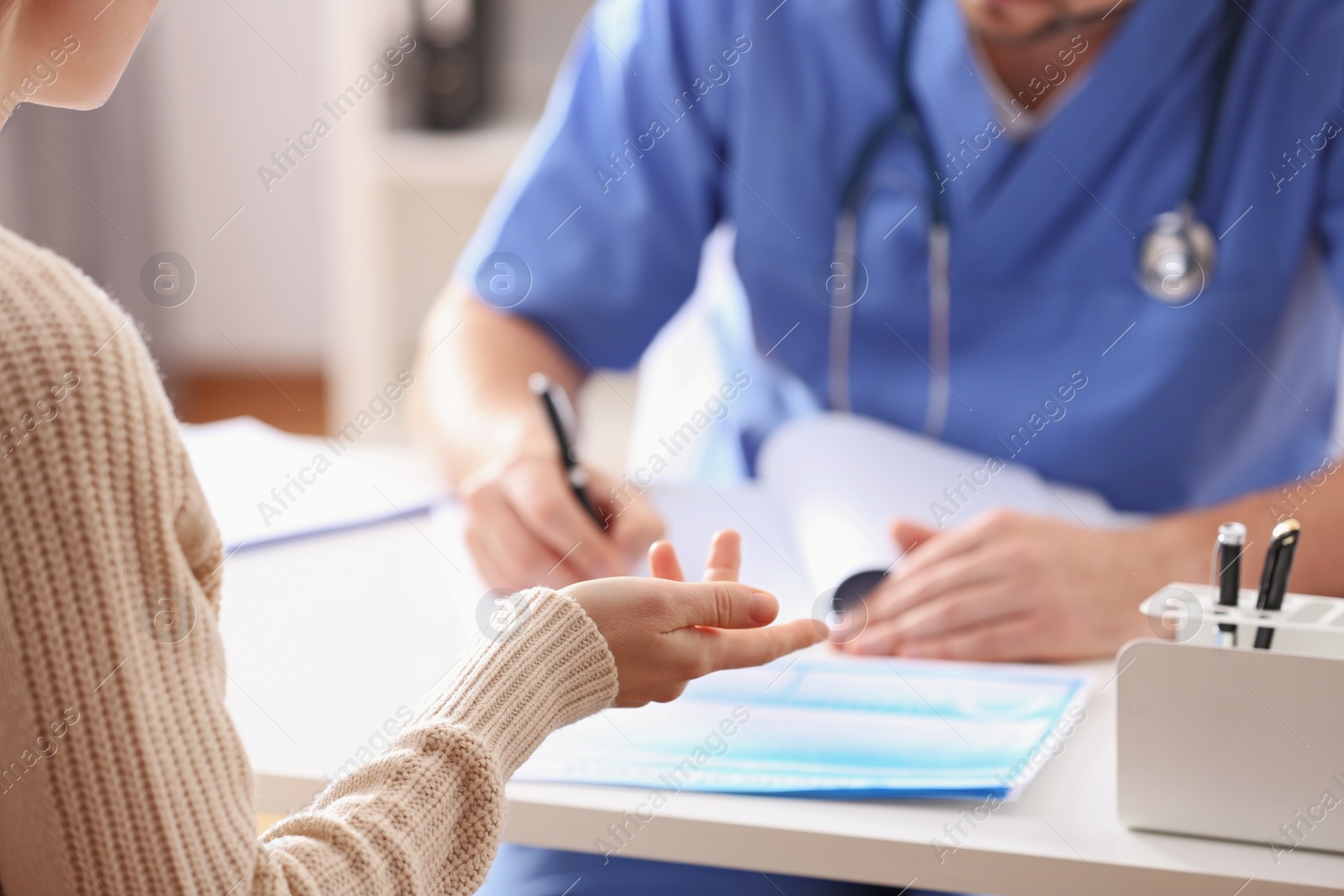 Photo of Doctor consulting patient at desk in clinic, closeup