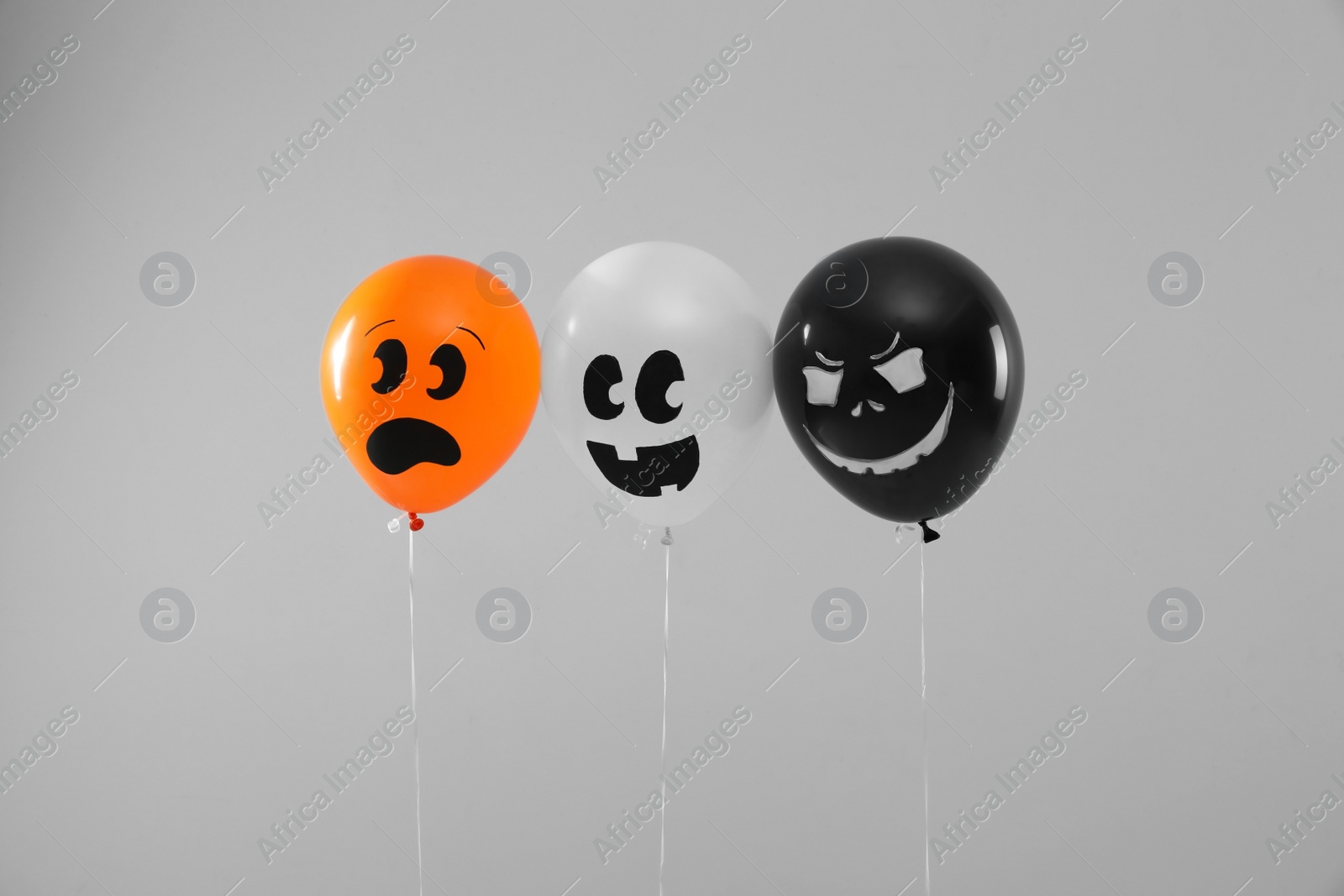 Photo of Spooky balloons for Halloween party on light grey background