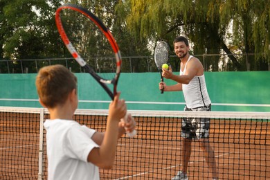 Father with his son playing tennis on court