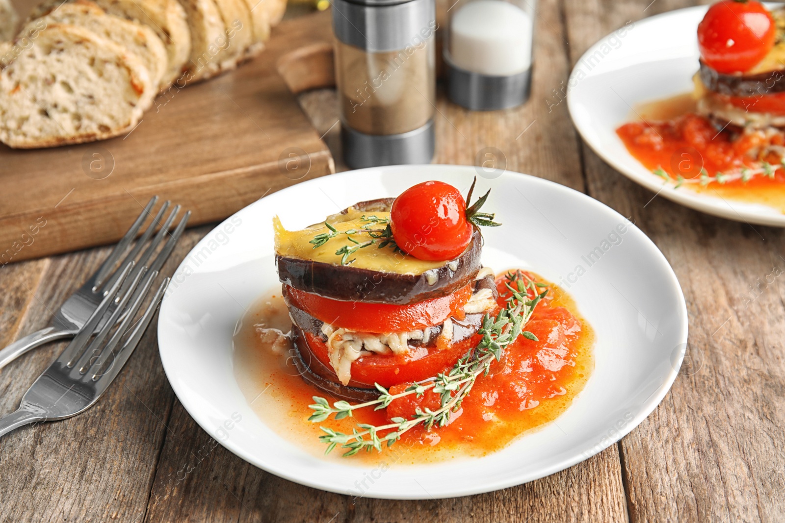 Photo of Baked eggplant with tomatoes, cheese and thyme on wooden table