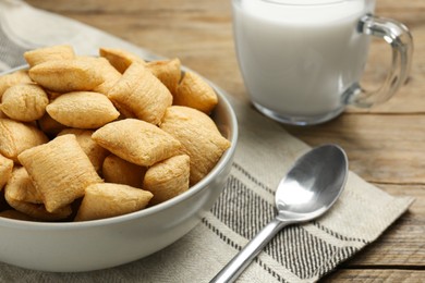 Photo of Bowl of sweet crispy corn pads and milk on wooden table, closeup. Breakfast cereal