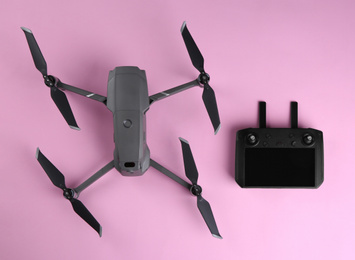Photo of Modern drone with controller on pink background, flat lay