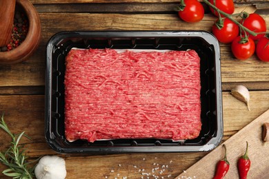 Raw fresh minced meat, tomatoes and other ingredients on wooden table, flat lay