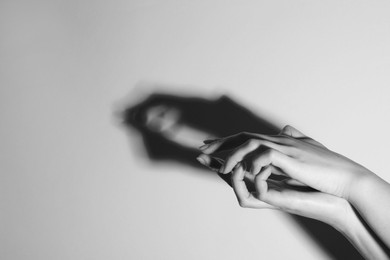 Shadow puppet. Woman making hand gesture like crocodile on light background, closeup with space for text. Black and white effect