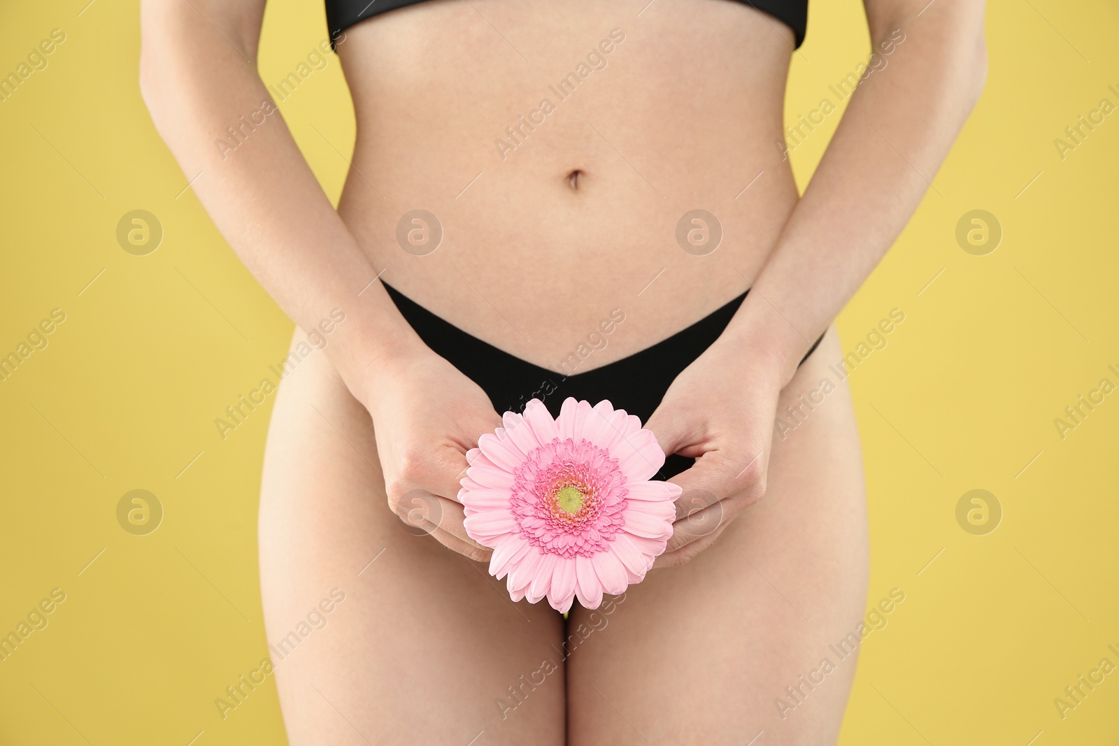 Photo of Gynecology. Woman in underwear with gerbera flower on yellow background, closeup