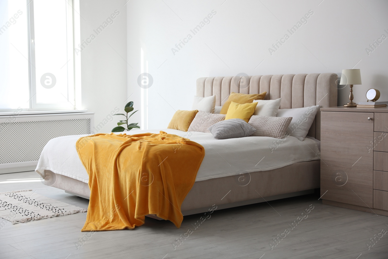 Photo of Stylish bedroom interior with soft yellow pillows and blanket