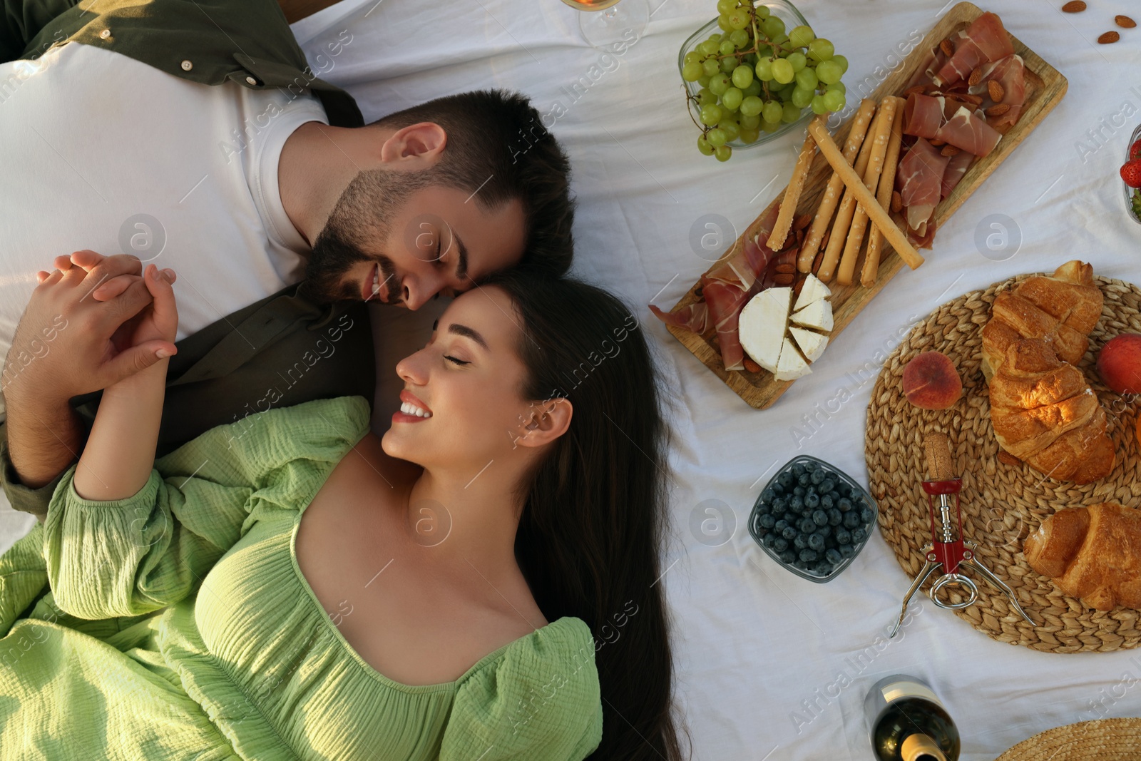 Photo of Romantic date. Beautiful couple resting on picnic blanket, top view