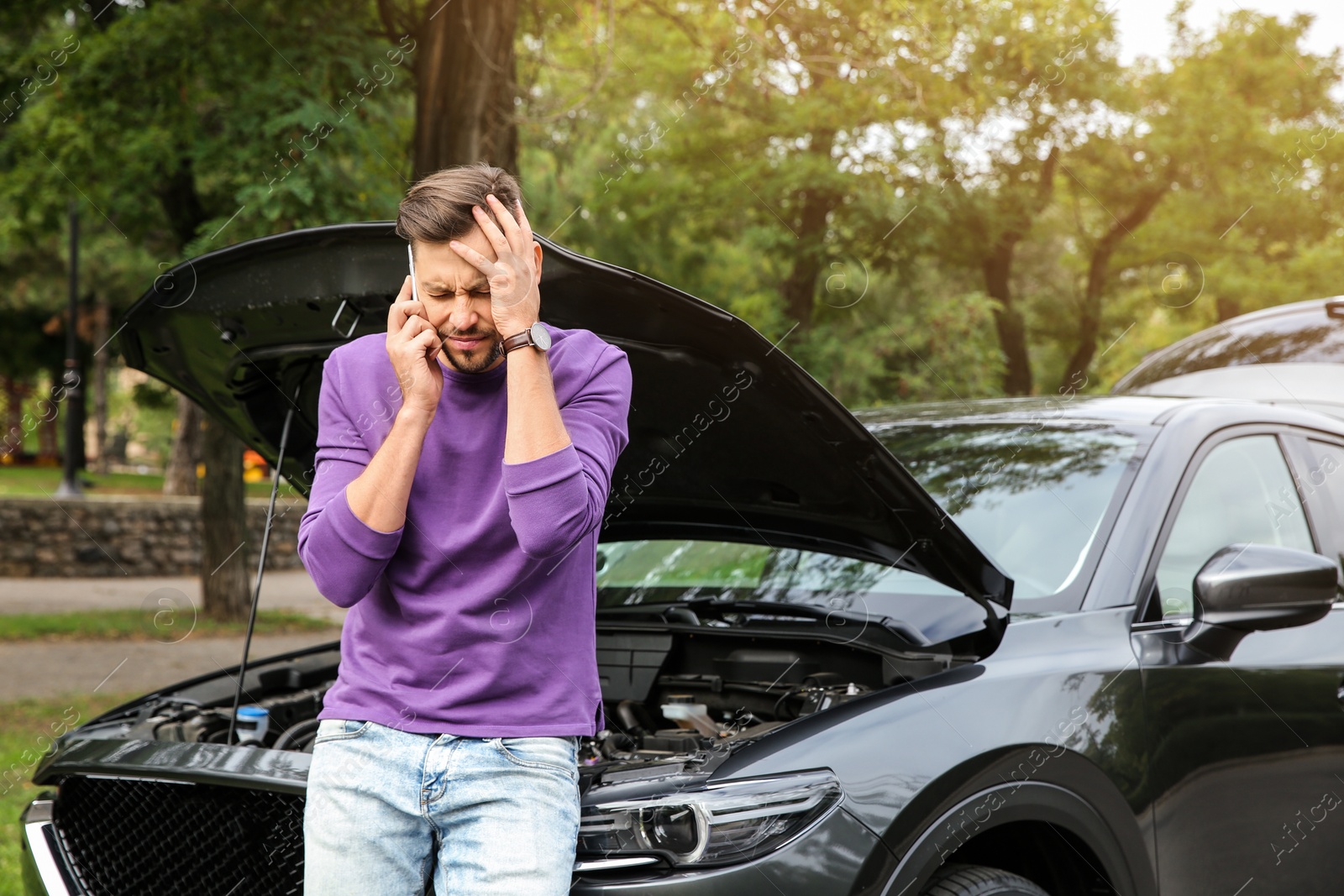 Photo of Man talking on phone near broken car outdoors