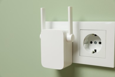 Wireless Wi-Fi repeater on light green wall indoors