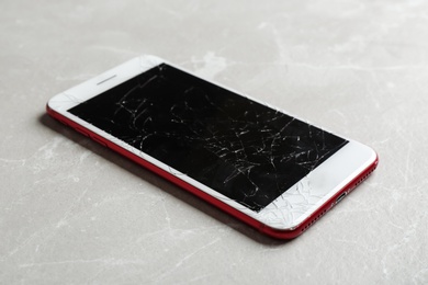 Photo of Modern smartphone with broken display on table. Device repair service