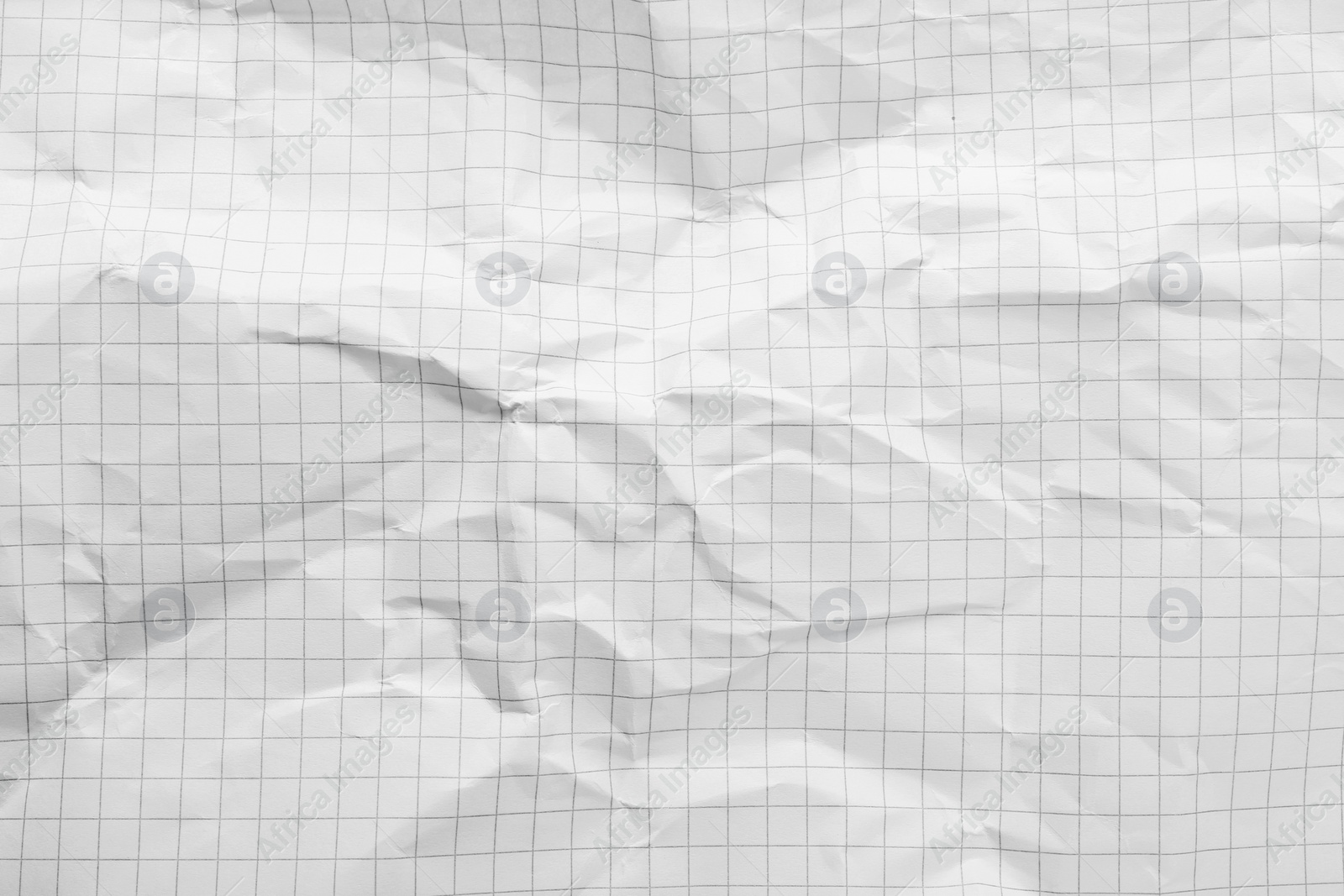 Photo of Crumpled checkered notebook sheet as background, top view