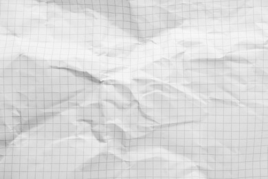 Photo of Crumpled checkered notebook sheet as background, top view