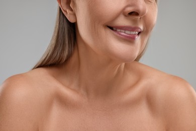 Mature woman with healthy skin on grey background, closeup