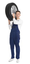 Male mechanic with car tire on white background