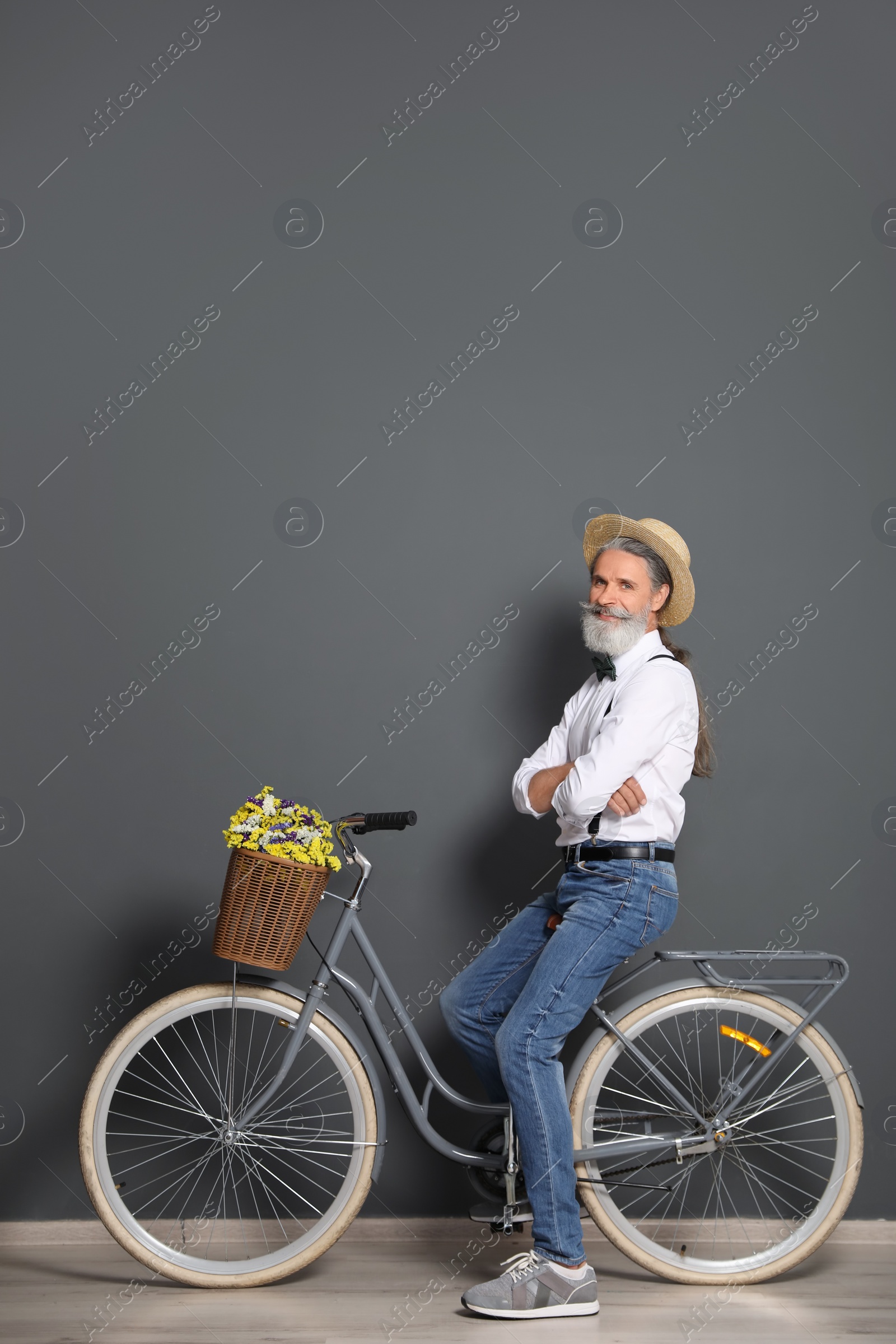 Photo of Portrait of handsome mature man with bicycle near color wall