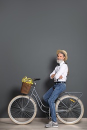 Portrait of handsome mature man with bicycle near color wall